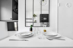 - une cuisine blanche avec deux assiettes et un four micro-ondes dans l'établissement Cosy Studio - Pyrénées, à Paris