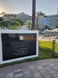 a sign on a sidewalk in a park at Address Beach Resort Fujairah Apartment 2 Bed Rooms and Small Bed Room - Ground Floor 3011 in Al Aqah