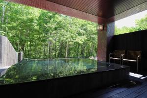 Suigan في Jozankei: حوض استحمام ساخن في غرفة مطلة على الأشجار