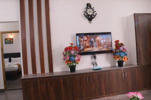uma televisão de ecrã plano em cima de um armário de madeira em Leo Home Stay em Tirupati