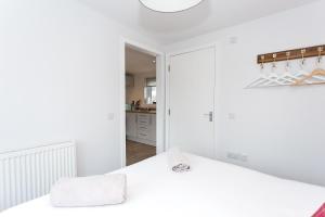 a white bedroom with a bed and a kitchen at Jack's Hideaway in Gatehouse of Fleet