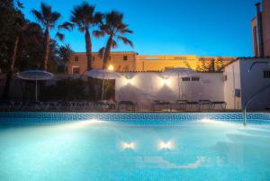 a swimming pool at night with umbrellas and chairs at Hotel Ecoavenida in Benicàssim