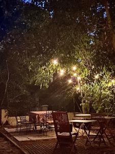 een groep tafels en stoelen onder een boom met verlichting bij chambre d'hôte chez l'habitant in Sète