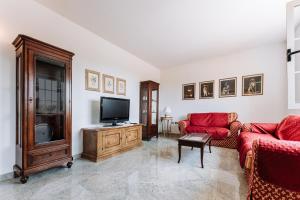 a living room with two red couches and a flat screen tv at Casa Antonietta in SantʼAnna Arresi