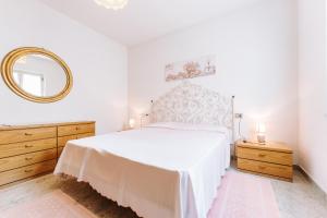 a white bedroom with a large bed and a mirror at Casa Antonietta in SantʼAnna Arresi