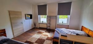 a bedroom with a bed and a desk and two windows at VILLA LINDENECK BUSiNESS in Bernburg