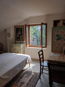 a bedroom with a bed and a desk and a window at Vivere in un bosco Casa Leonardo in Villar Perosa