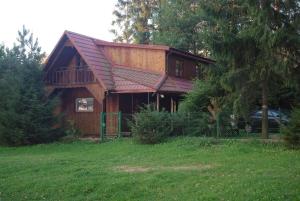 une maison avec un toit rouge sur un champ vert dans l'établissement Okuninka Domek nad brzegiem jeziora Białe, à Okuninka