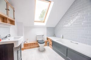 a bathroom with a toilet and a sink and a window at The Old Coach House, Leiston in Leiston