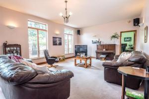 a living room with two leather couches and a tv at The Old Coach House, Leiston in Leiston