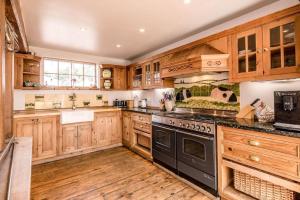 a large kitchen with wooden cabinets and black appliances at The Old Coach House, Leiston in Leiston