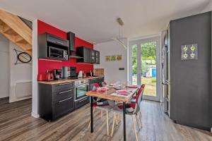une cuisine avec une table et un mur rouge dans l'établissement KerMad - Maison avec jardin, à Le Relecq-Kerhuon