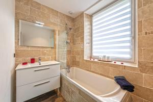 a bathroom with a tub and a sink and a mirror at KerMad - Maison avec jardin in Le Relecq-Kerhuon +6 photos