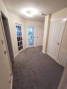 an empty hallway with white doors and carpeted floors at Slateford Road Modern Apartment in Edinburgh