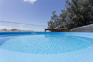 a large pool of blue water with trees in the background at Quinta das Rosas Villas in Ribeira Grande