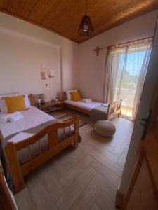 a bedroom with two beds and a large window at homonatura. sense of native living. in Pýrgos