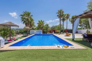 a swimming pool in a yard with palm trees at Casa Rural Villa Felisa in La Puebla de Cazalla