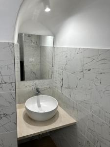 een witte wastafel in een badkamer met marmeren muren bij SUITE 1 in Palo del Colle