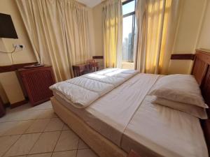 a bedroom with a large white bed with a window at Moshi Leopard Hotel in Moshi