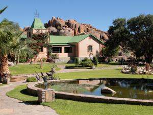 ein Haus mit einem Teich inmitten eines Parks in der Unterkunft Gondwana Canyon Lodge in Kanebis