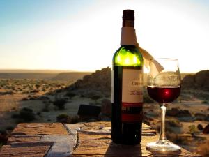 eine Flasche Wein neben einem Glas Wein in der Unterkunft Gondwana Canyon Lodge in Kanebis