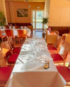 Hotel-Restaurant Domaine de la Grande Garenne في Neuvy-sur-Barangeon: طاولة طويلة في مطعم مع كؤوس النبيذ