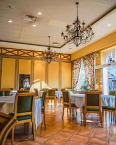 uma sala de jantar com mesas e cadeiras e um lustre em Hotel-Restaurant Domaine de la Grande Garenne em Neuvy-sur-Barangeon