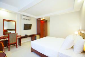 - une chambre avec un lit, un bureau et une télévision dans l'établissement Sunshine Boutique Hotel Phu My Hung, à Hô-Chi-Minh-Ville