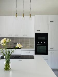 a white kitchen with a vase of flowers on a counter at Maison Comtale in Rochefort