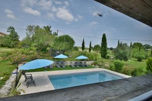 una piscina con sillas y sombrillas en un jardín en Le Refuge Confortable gîte avec terrasse, en Castelnau-sur-lʼAuvignon