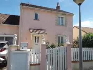 uma cerca branca em frente a uma casa em la maison rose 2 chambres a louer avec lits 2 personnes em Nevers