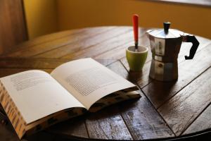 an open book on a wooden table next to a coffee maker at Famme sta cuiete appartamento Napoli centro in Naples