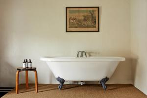 uma banheira branca na casa de banho com uma fotografia na parede em The Sherborne Arms em Northleach