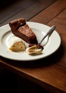 un trozo de pastel de chocolate y helado en un plato en The Sherborne Arms, en Northleach