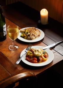 two plates of food and a glass of wine on a table at The Sherborne Arms in Northleach