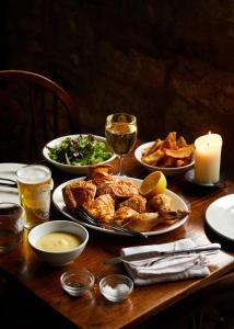 a wooden table with plates of food and a candle at The Sherborne Arms in Northleach