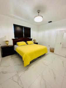 a bedroom with a bed with a yellow blanket at Cozy Guest House 1.9 miles from Hard Rock Stadium in Miami Gardens