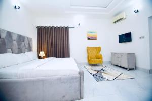 - une chambre avec un lit et une chaise jaune dans l'établissement Oasis Villa Lekki, à Lekki