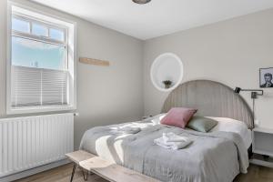 a white bedroom with a bed and a window at Two bedroom downtown apartment with balcony in Akureyri