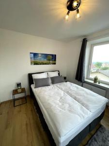 a large white bed in a bedroom with a window at Homestay - Luxus Ferienwohnung in Bad Griesbach