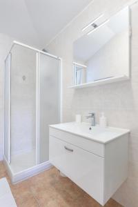 a white bathroom with a shower and a sink at Sea view by Moro 3 in Malinska +27 photos