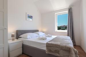 a bedroom with a bed with white sheets and a window at Sea view by Moro 3 in Malinska