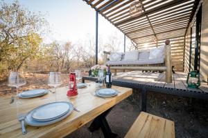 - une table avec des assiettes et des verres à vin sur la terrasse dans l'établissement Kamoka Camp, à Hoedspruit