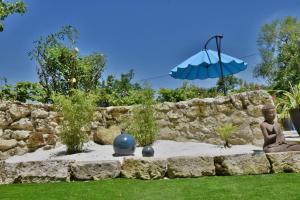 a stone wall with a statue and an umbrella at Chambre d'hôtes Le Bol d'Air avec jacuzzi in Castelnau-sur-lʼAuvignon