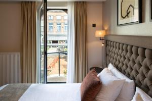 a hotel room with a bed and a large window at Dukes' Academie Brugge - by Dukes' Hotel Collection in Bruges