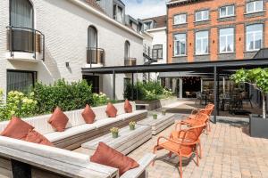 a patio with benches and chairs in front of a building at Dukes' Academie Brugge - by Dukes' Hotel Collection in Bruges