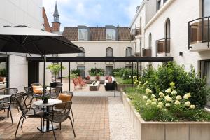 an outdoor patio with tables and chairs and an umbrella at Dukes' Academie Brugge - by Dukes' Hotel Collection in Bruges