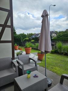 un patio con sombrilla, sillas y mesa en Apartamenty z Klimatem, en Ustka