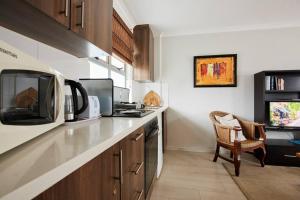 a kitchen with a counter with a tv and a chair at The Rondebosch in Cape Town