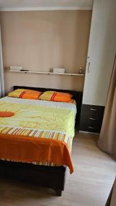 a bedroom with a bed with orange and yellow sheets at Apartman Batuta in Budva